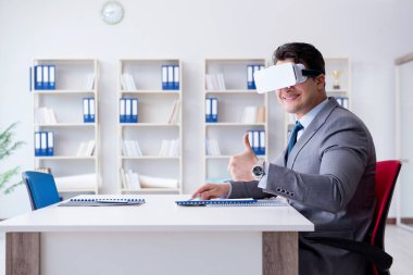 Ofiste sanal gerçeklik gözlüklü bir iş adamı var.