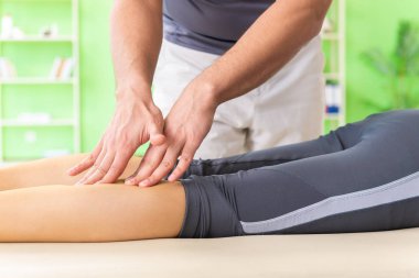 Genç doktor masör hastaya masaj yapıyor. 