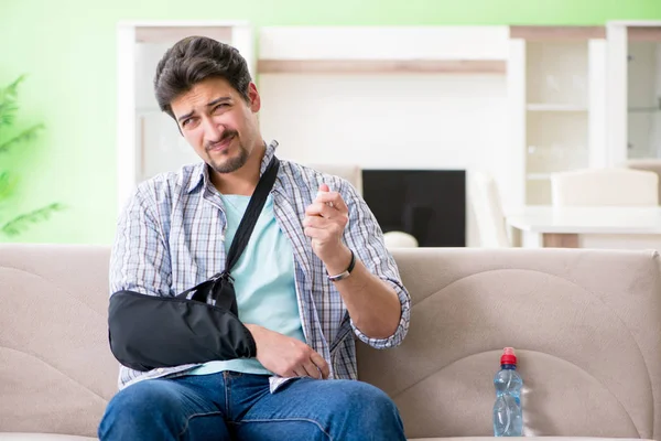 Jovem estudante com lesão na mão sentado no sofá — Fotografia de Stock