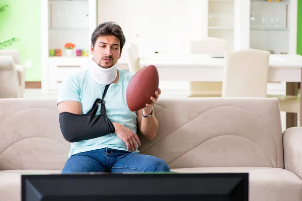 Homem com lesão no pescoço e braço assistindo futebol americano na tv — Fotografia de Stock