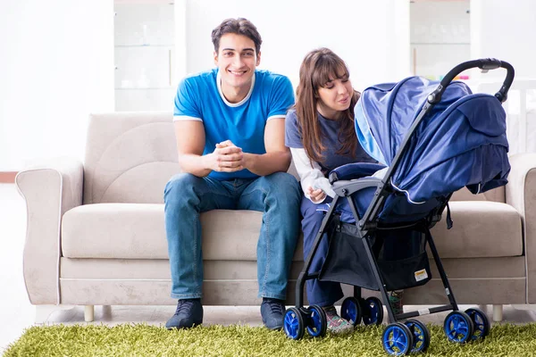 Bebekleri bebek arabasında oturan genç ebeveynler.