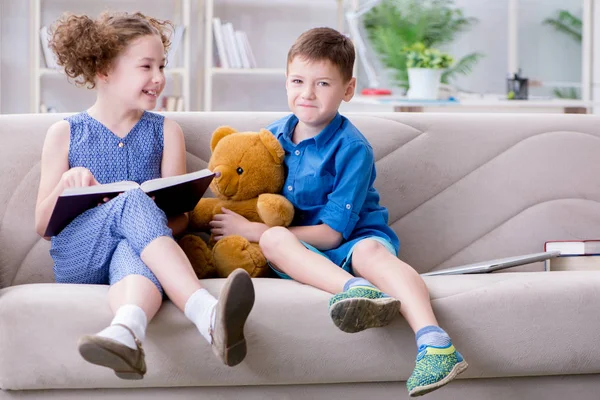 Evde kitap okuyan iki çocuk.