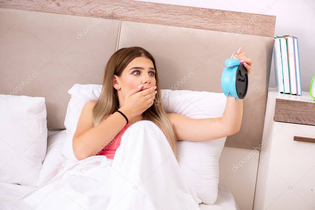 Young woman waking up in the morning in bed