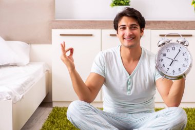 Genç adam yatak odasında yoga yapıyor.