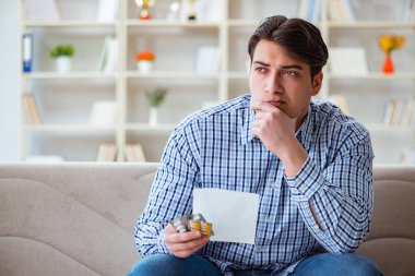 Kanepede ilaç ve reçeteyle oturan genç adam.