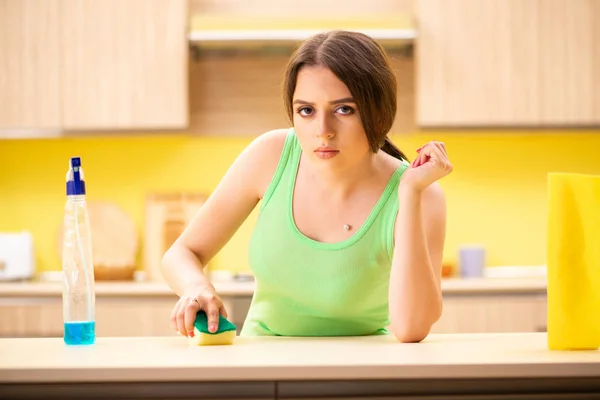 Jonge mooie vrouw polijsten tafel in de keuken — Stockfoto