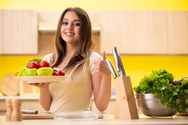 Young woman preparing salad at home in kitchen — Stock Photo, Image