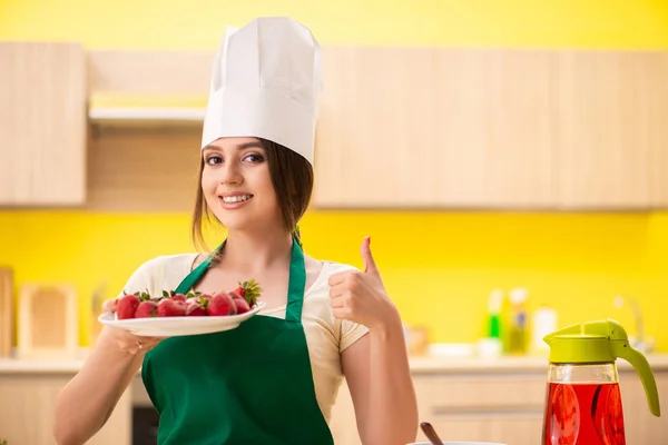 Ung kvinnlig kock som äter jordgubbar — Stockfoto