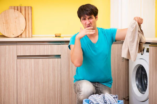 Genç koca evde çamaşır yıkıyor. — Stok fotoğraf
