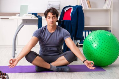 Ofiste egzersiz yapan genç bir erkek.