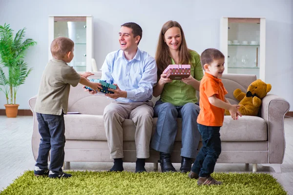 Padres jóvenes repartiendo regalos de Navidad en casa — Foto de Stock