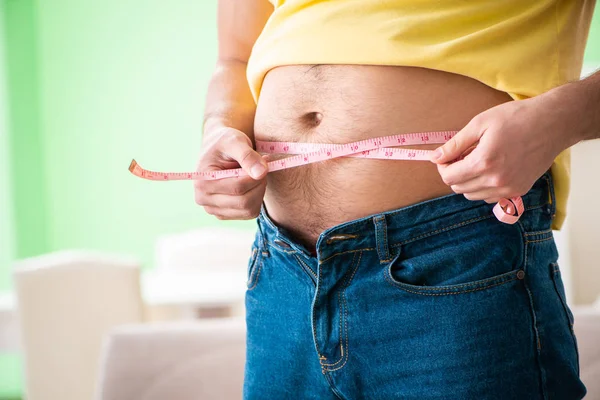 Hombre midiendo grasa corporal con cinta métrica en concepto de dieta — Foto de Stock