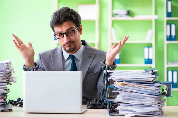 Empregado acorrentado à sua mesa devido à carga de trabalho — Fotografia de Stock