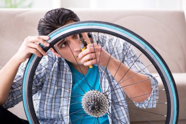 Evde bisiklet tamir eden genç bir adam.