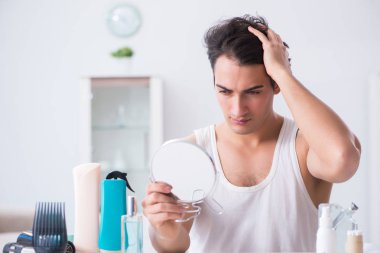 Genç yakışıklı adam aynaya bakıyor. 