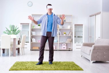 Evde sanal gerçeklik gözlüklü bir adam oynuyor.