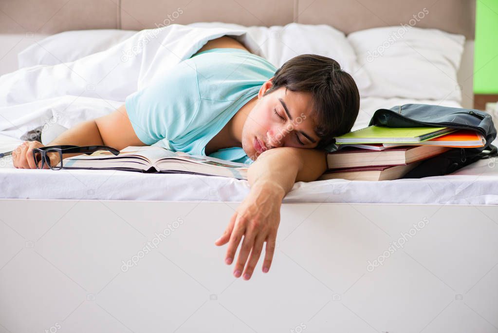 Student preparing for exams at home in bedroom lying on the bed