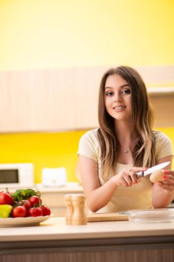 Genç bayan mutfakta salata hazırlıyor.