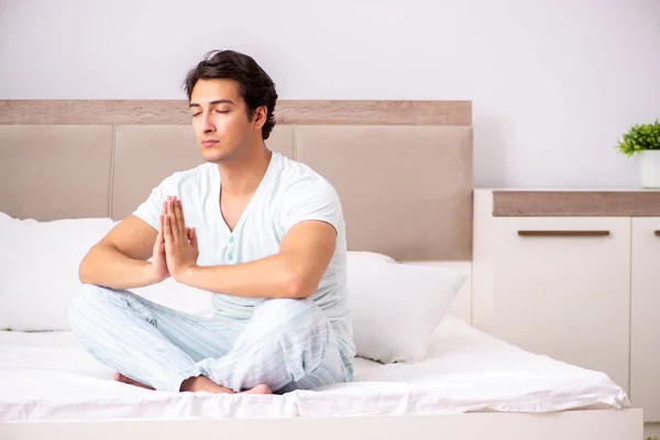 Joven haciendo yoga en la cama —  Fotos de Stock