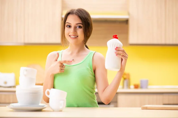 Jovem mulher de limpeza e lavagem de pratos na cozinha — Fotografia de Stock