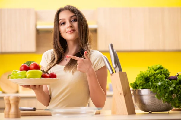 Young woman preparing salad at home in kitchen — Stock Photo, Image