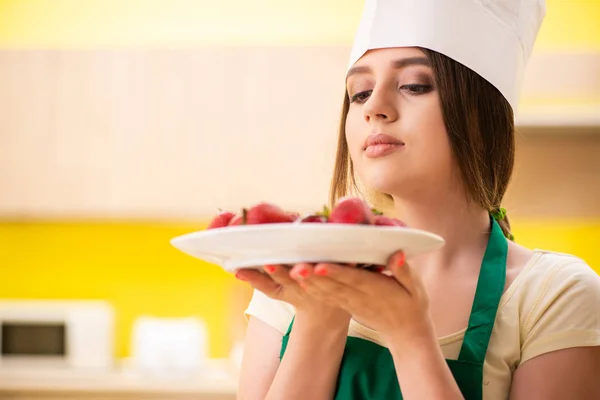 Jovem cozinheira comendo morangos — Fotografia de Stock