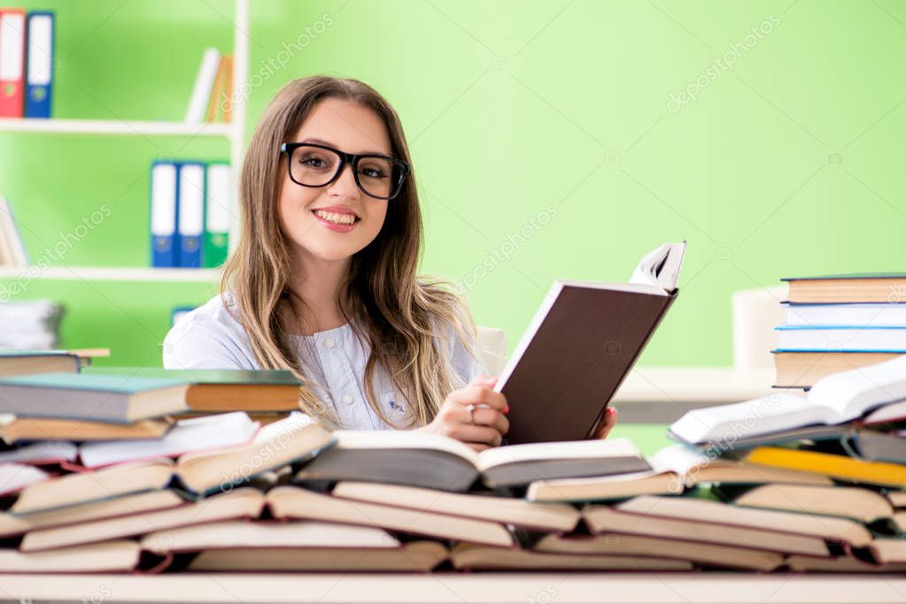 Young female student preparing for exams with many books 