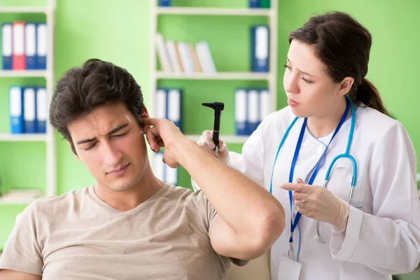여성 의사가 검진을 받는 동안 환자 의귀를 점검 한다 — 스톡 사진