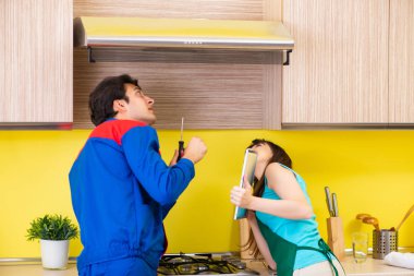 Mutfakta müteahhitle birlikte çalışan bir kadın tamir hakkında konuşuyor.