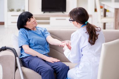 Genç doktor yaşlı kadını muayene etmek için ziyaret ediyor.