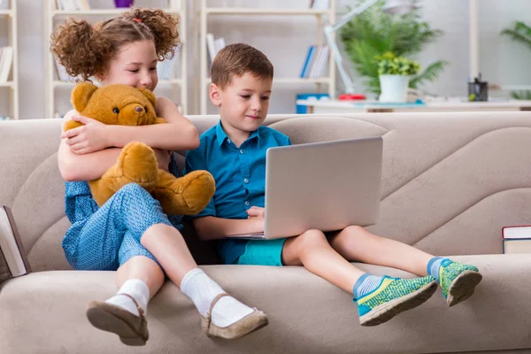 Due bambini seduti al computer portatile a casa — Foto Stock