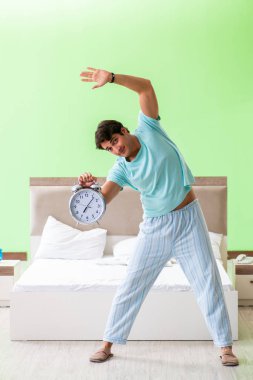 Pijamalı genç adam sabah egzersizi yapıyor. 
