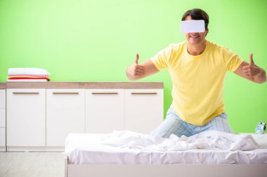 Yatak odasında sanal gözlüklü genç adam. 