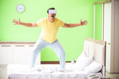 Yatak odasında sanal gözlüklü genç adam. 