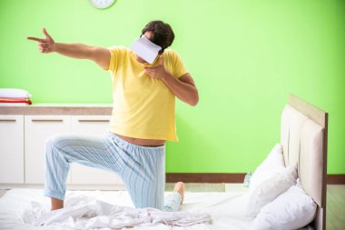 Yatak odasında sanal gözlüklü genç adam. 