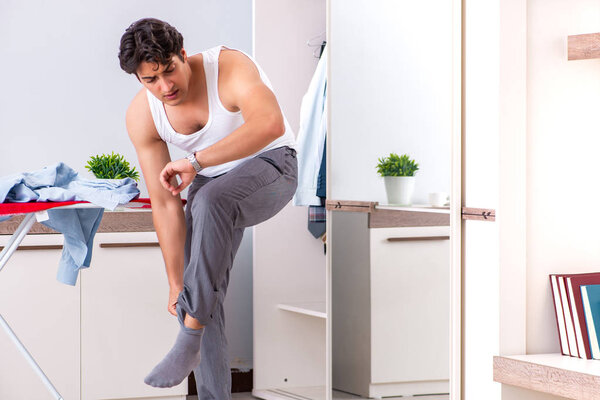 Young man ironing in the bedroom 