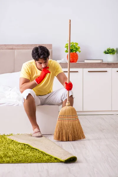 Giovane uomo bello pulizia in camera da letto — Foto Stock