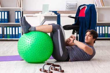 Ofiste egzersiz yapan genç bir erkek.