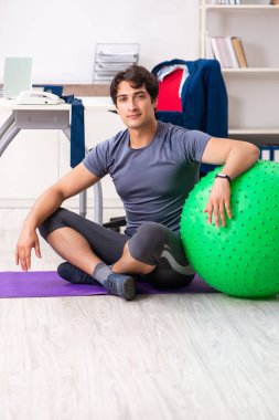 Ofiste egzersiz yapan genç bir erkek.