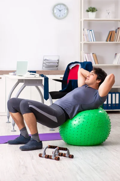 Young male employee exercising in the office — Stock Photo, Image