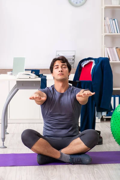 Young male employee exercising in the office — Stock Photo, Image