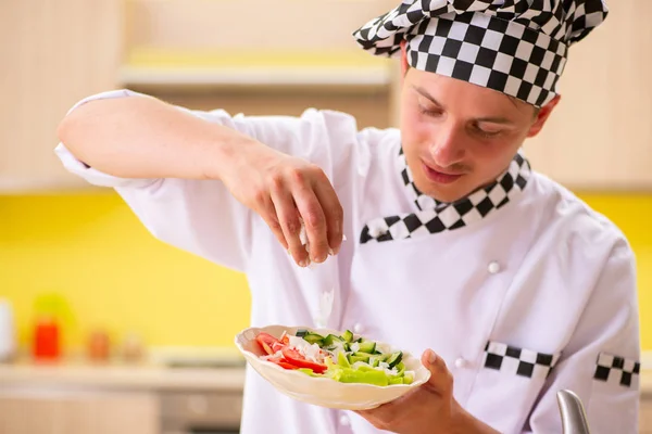 Jovem cozinheiro profissional preparando salada na cozinha — Fotografia de Stock