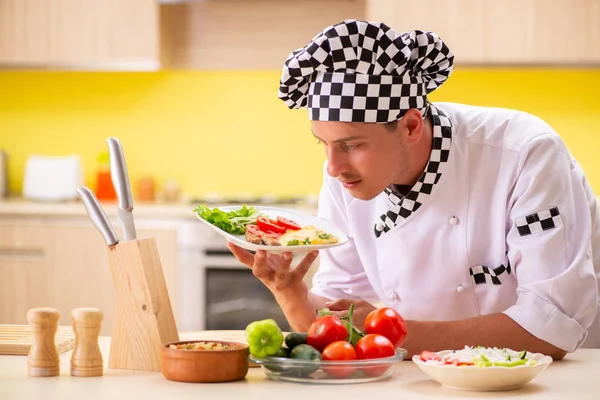 Joven cocinero profesional preparando ensalada en la cocina — Foto de Stock