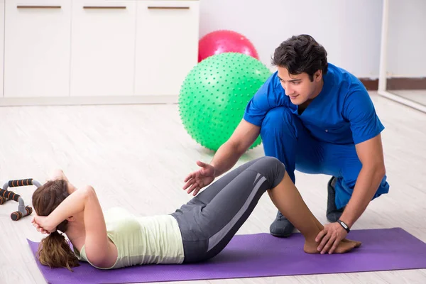 Fitness instructor helping sportsman during exercise — Stock Photo, Image
