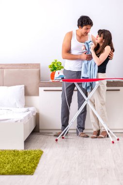 Genç kadın kocası için ütü yapıyor.