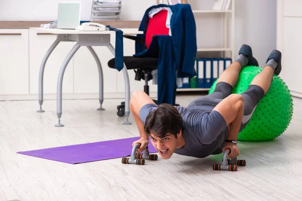 Young male employee exercising in the office — Stock Photo, Image