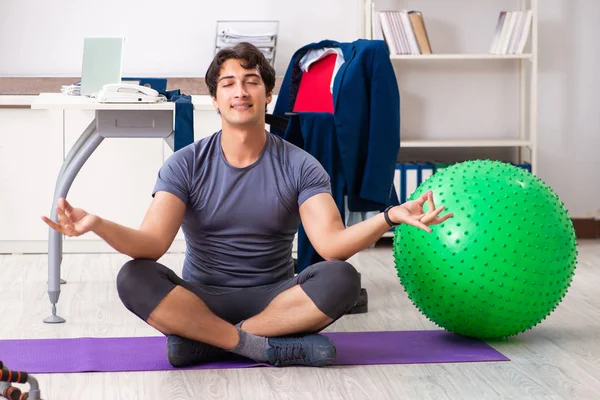 Jonge mannelijke werknemer oefent in het kantoor — Stockfoto