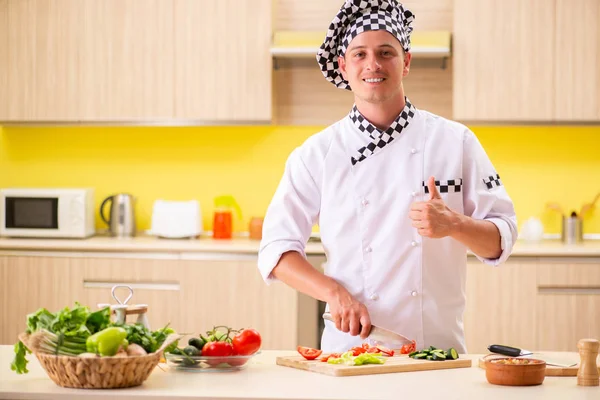 Jovem cozinheiro profissional preparando salada na cozinha — Fotografia de Stock