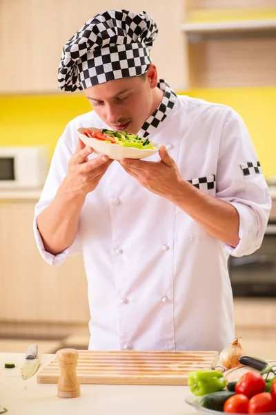 Jovem cozinheiro profissional preparando salada na cozinha — Fotografia de Stock