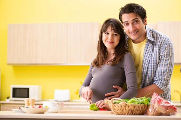 Hombre y mujer embarazada preparando ensalada en la cocina — Foto de Stock